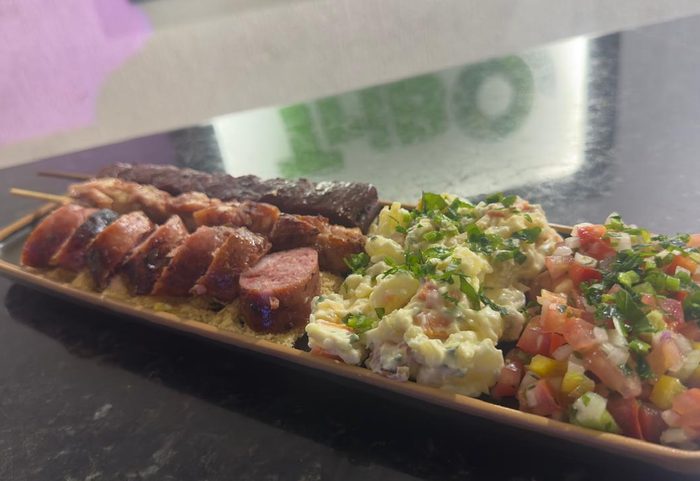 Prato de churrasco com espetinhos, maionese, farofa e vinagrete