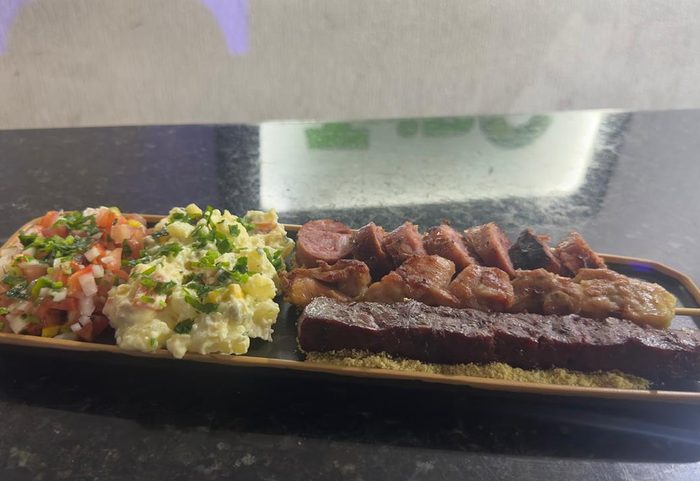 Prato de churrasco com espetinhos, maionese, farofa e vinagrete