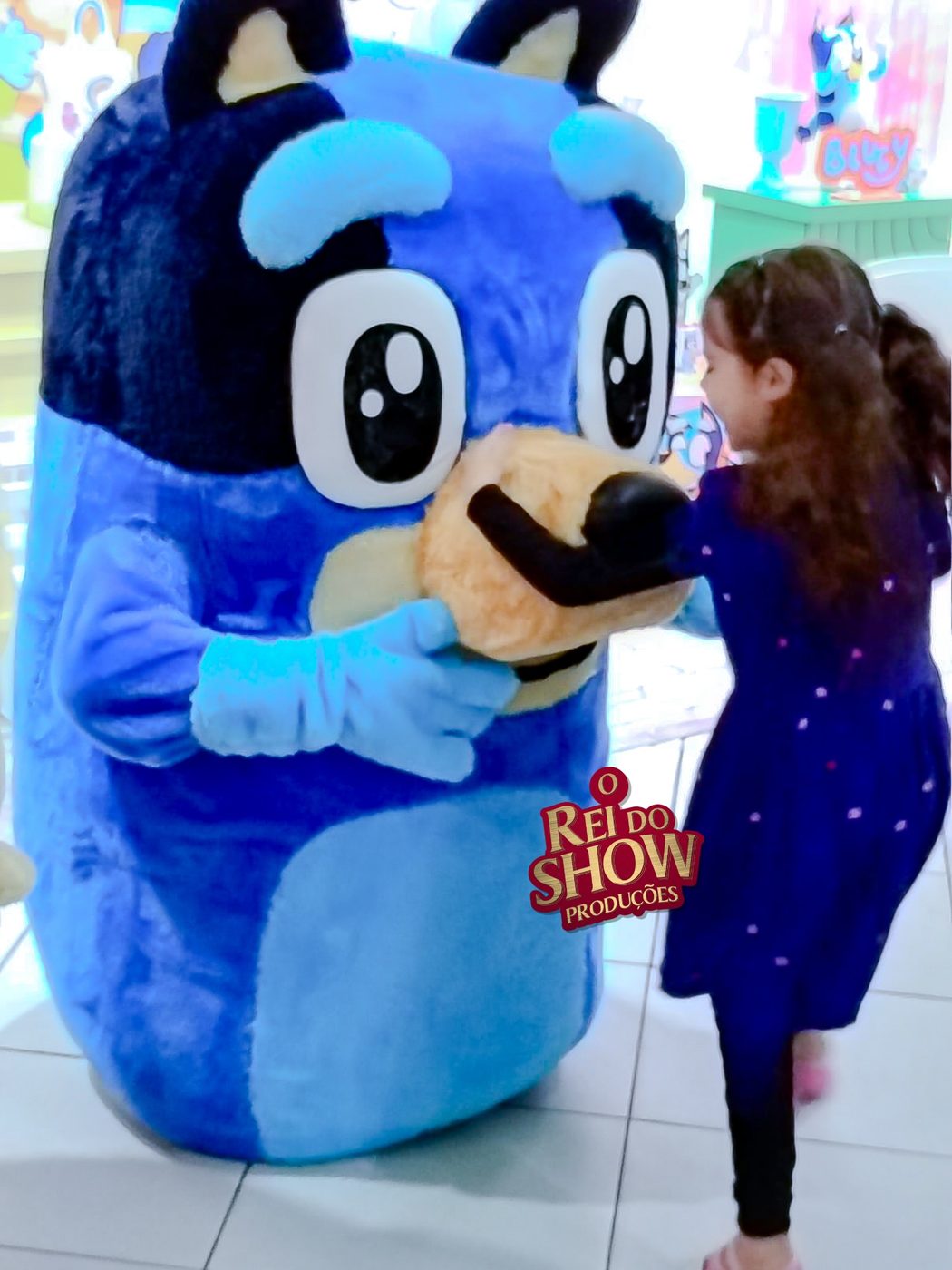 Boneco de corpo inteiro do Bluey brincando com uma criança na festa